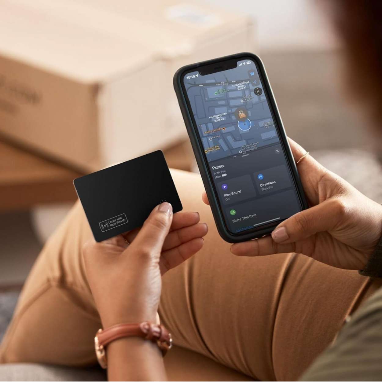 Woman holding a Find My tracker in her hand next to her smartphone